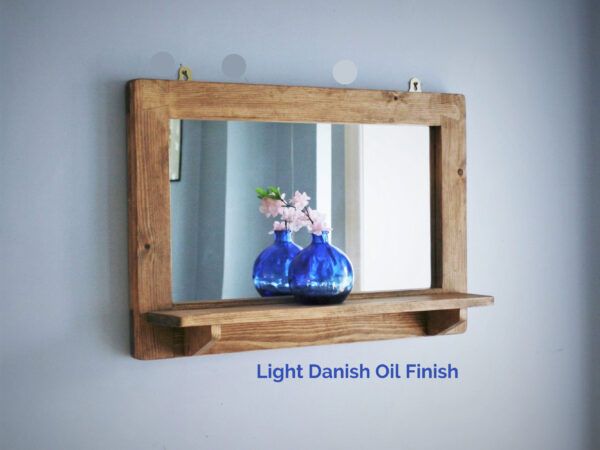Wooden mirror with shelf in light wood finish.