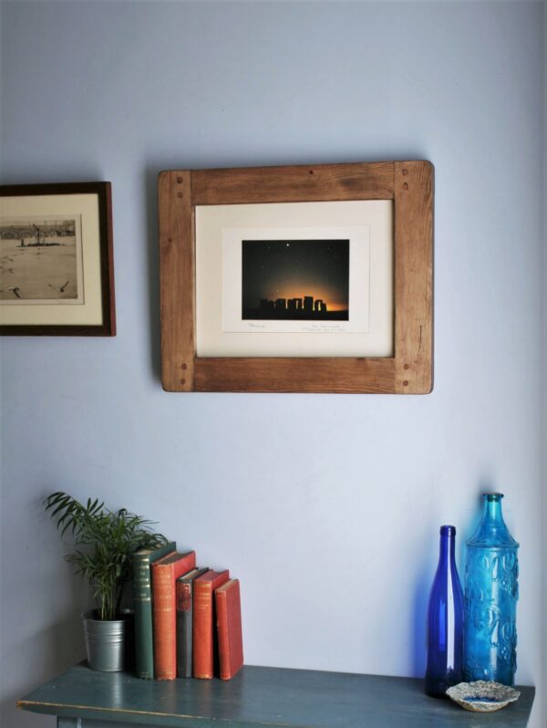 Large A3 picture frame in chunky natural wood, on the wall with blue glass ornaments and vintage books below