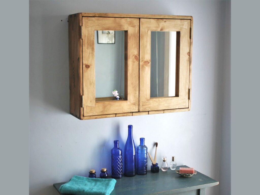 Large double mirror door wooden bathroom cabinet with cosmetic bottles on the table below.