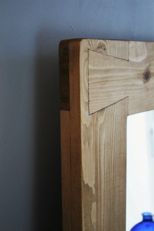 Chunky wooden mirror with a thick frame and dovetail joint as functional decoration.