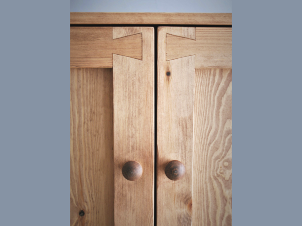 Large bathroom armoire cabinet with double doors and round wooden handles.