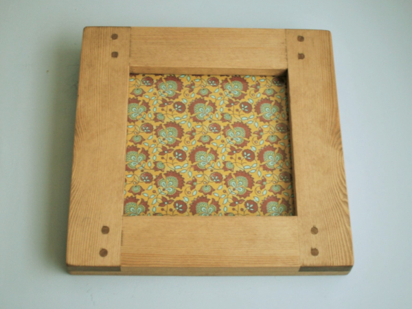 Square wooden picture frame in natural chunky rustic wood; low view.