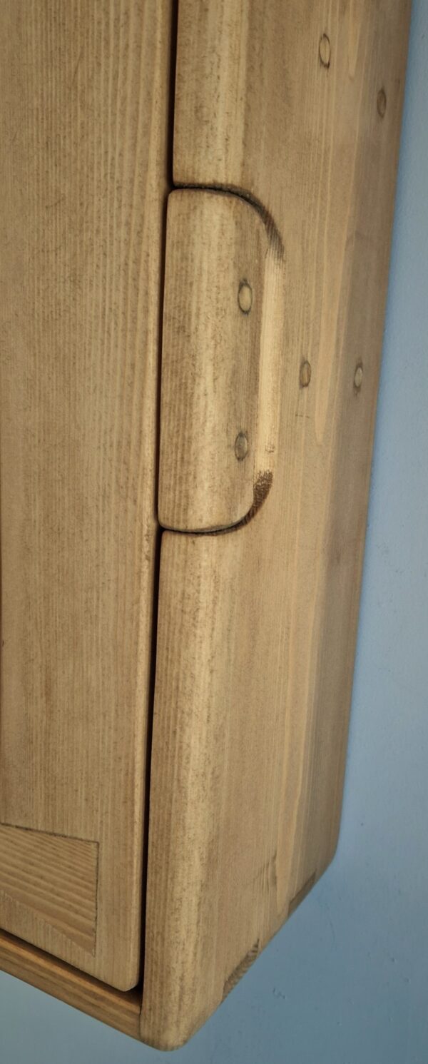 Detail of integrated handle for handmade wooden bathroom cabinet.