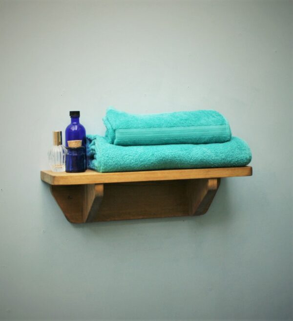 Small wooden bathroom shelf in chunky natural wood. For cosmetics, plants and towels. Side view, handmade in Somerset UK