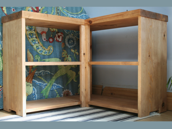 Low wooden corner bookcase, low view of shelf. Chunky natural wood shelves, handmade in Somerset UK.