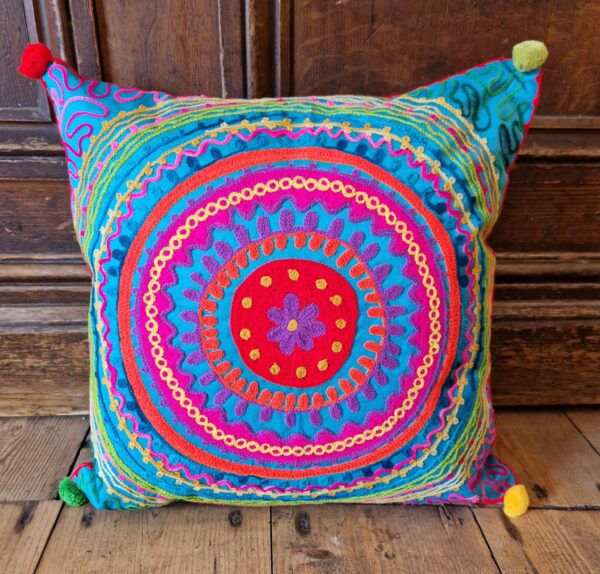 Colourful embroidered cushion cover close up, abstract pattern in pink, blue and green. Bohemian rustic homeware from Somerset.