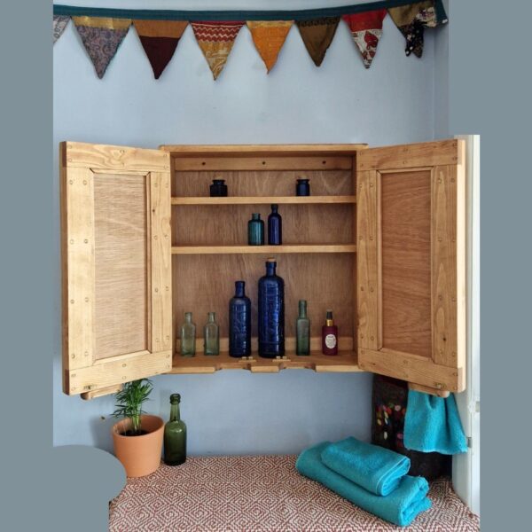 Wooden medicine cabinet with mirror doors open and boho silk bunting