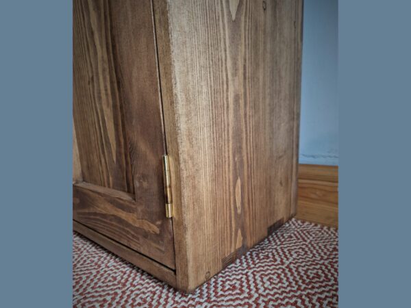 Detail of the feet of a wooden kitchen larder cupboard.