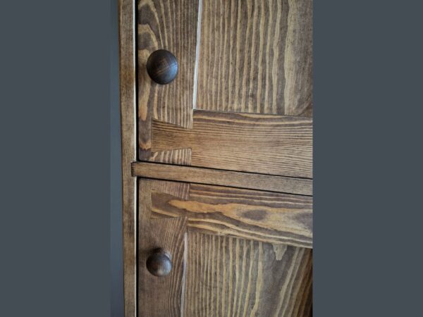 Close up of round handles on wooden kitchen larder cupboard.